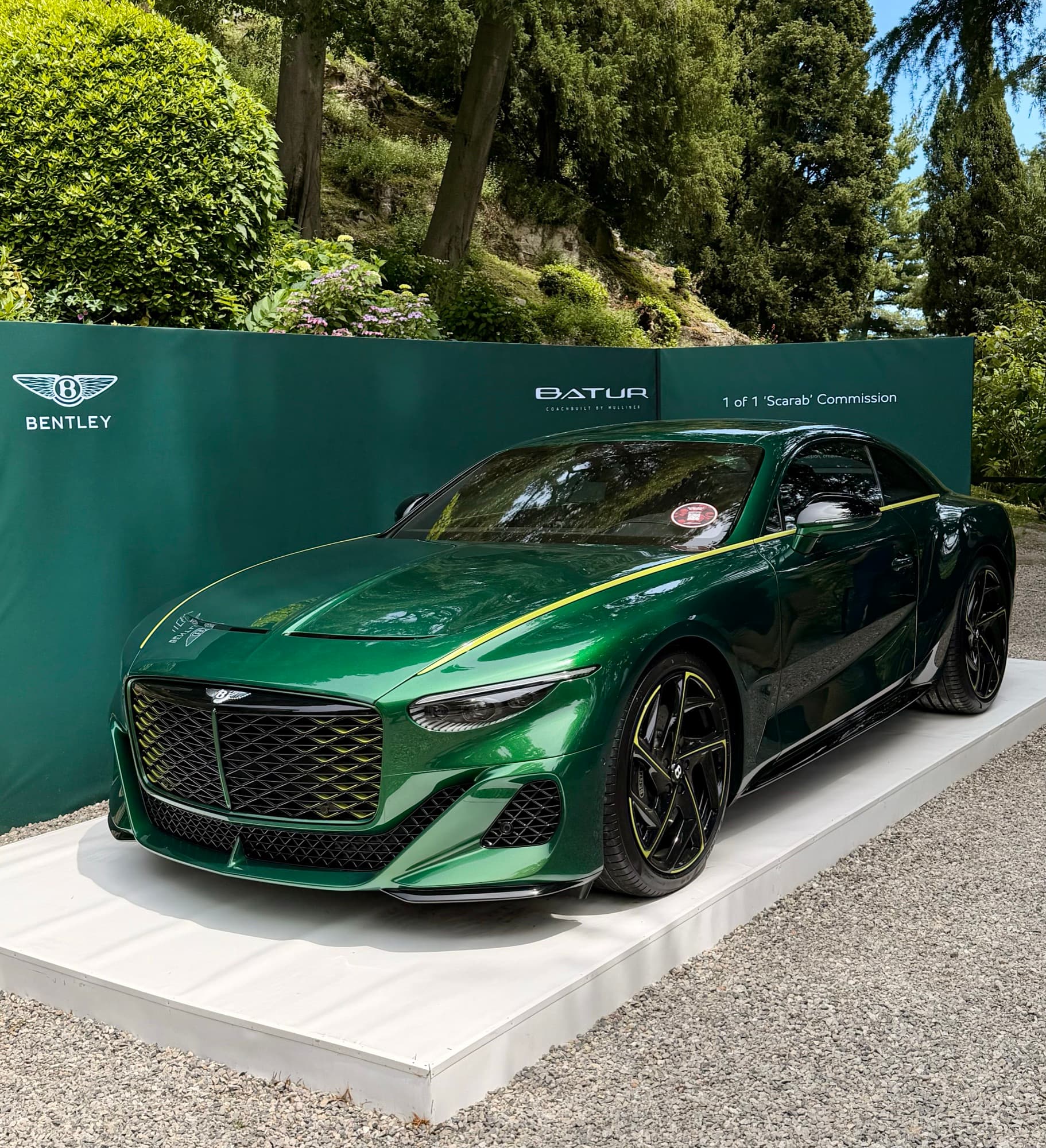 A dark green Bentley Batur on a concours display stand, its board naming it a one-of-one Scarab commission.