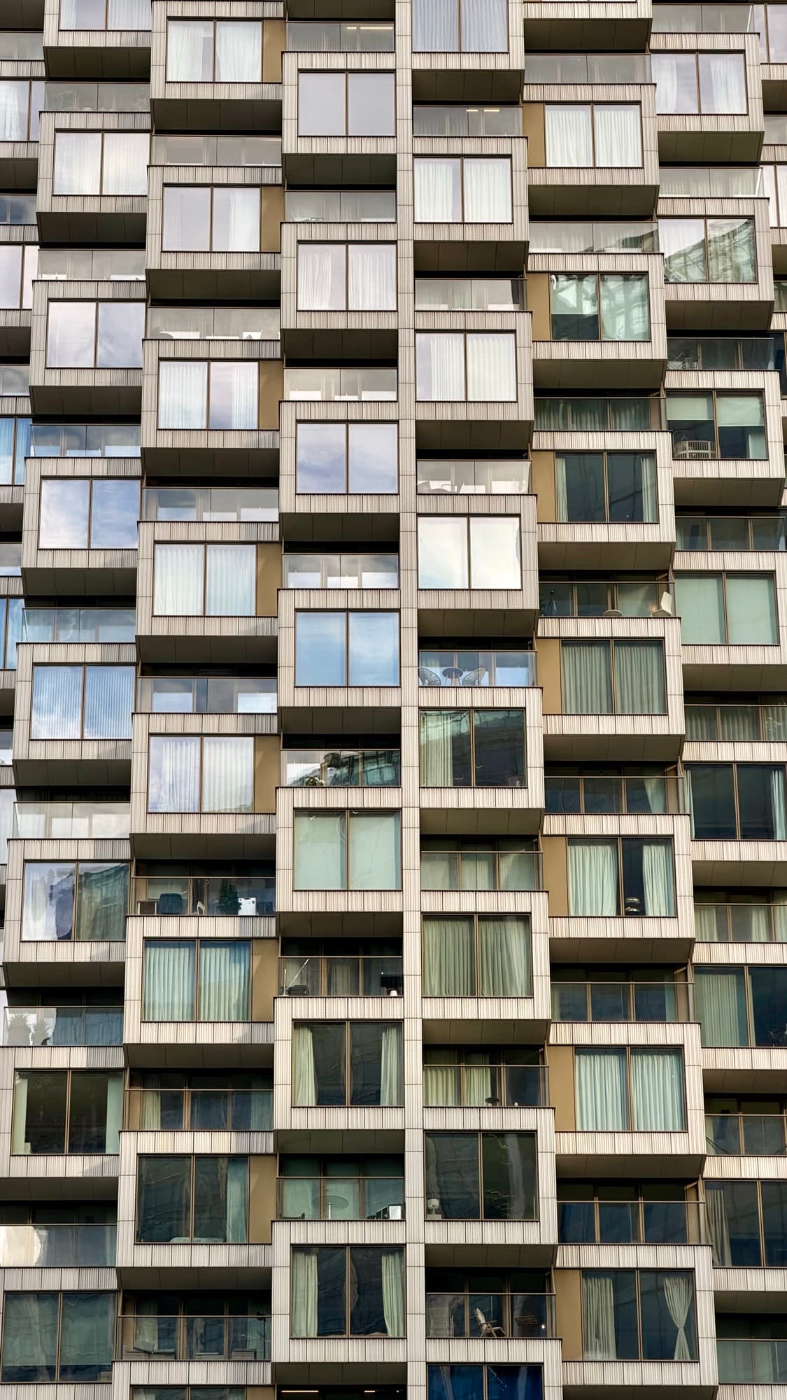 The face of an apartment tower, balconies and windows repeating to every edge of the frame.